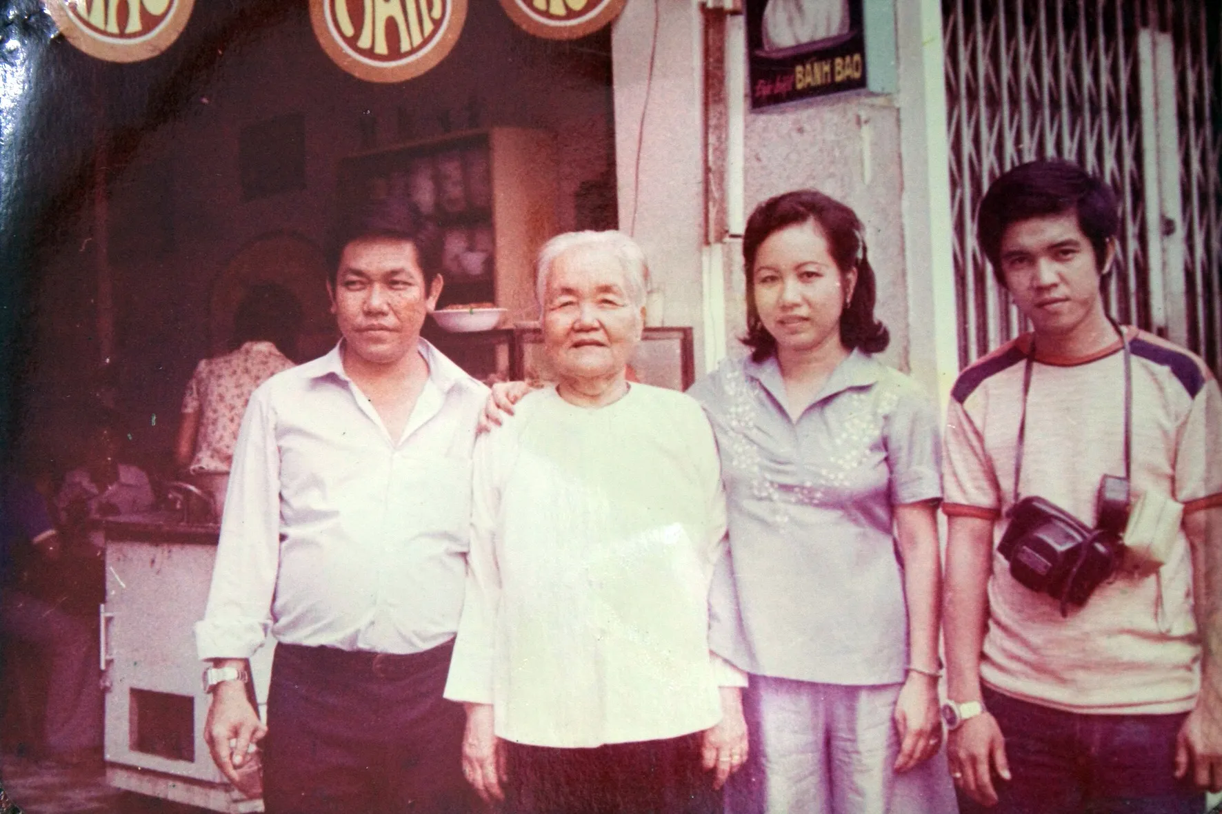 An older woman stands with three younger family members in front of the shop